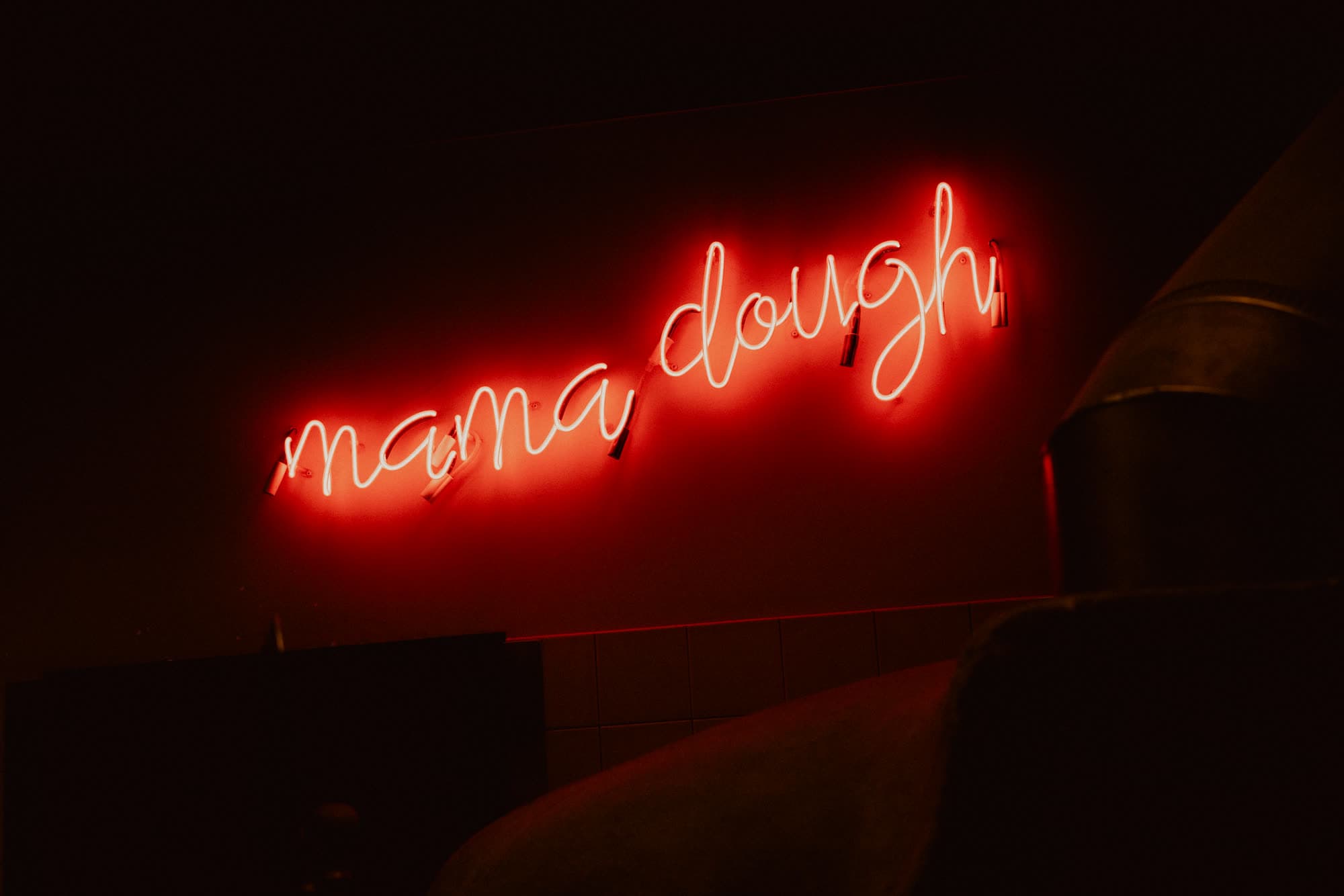The Mama Dough neon sign glowing red